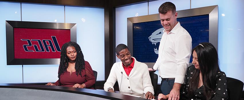 Professor working with students in television studio on campus.